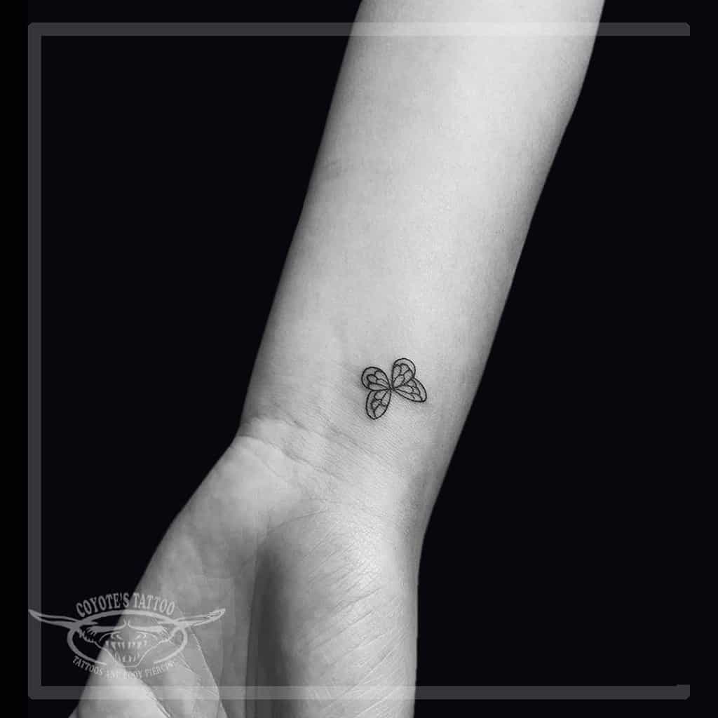 Tiny minimalist butterfly tattoo on the wrist, featuring fine black outlines for a delicate and subtle design.