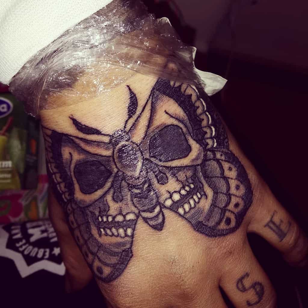 Bold black and grey death moth tattoo on the hand, featuring skull details for a striking and gothic-inspired design.