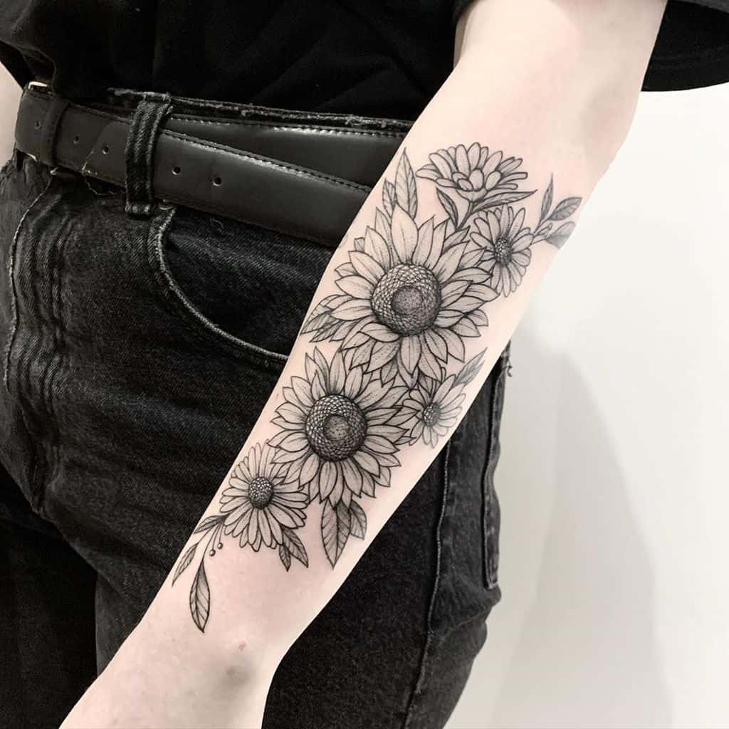Black and grey forearm tattoo featuring multiple sunflowers with fine line details, intricate shading, and delicate leaves for an elegant floral design.