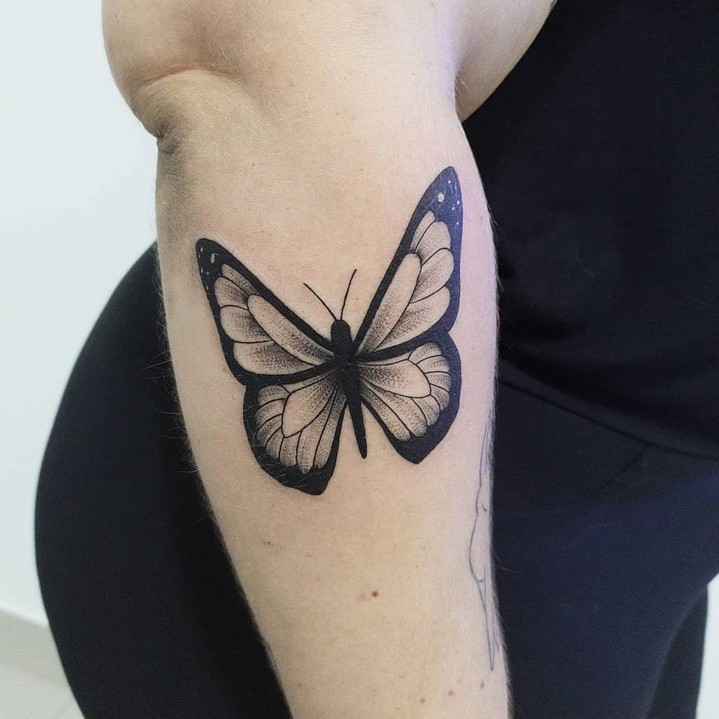 Elegant black and grey butterfly tattoo on the forearm with fine shading, creating a delicate and realistic design.