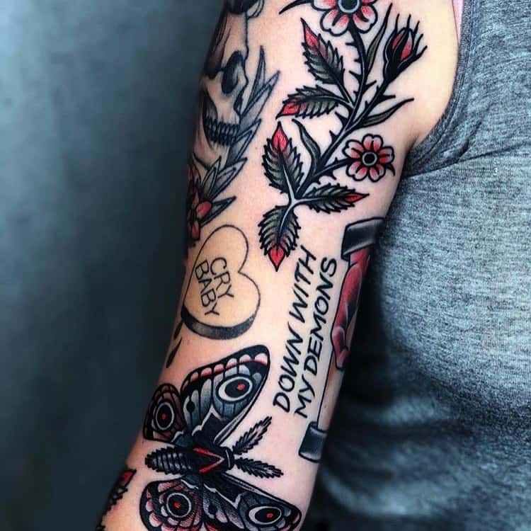 Bold traditional-style tattoo sleeve featuring a black and red butterfly, flowers, a dagger, and text elements for a striking design.