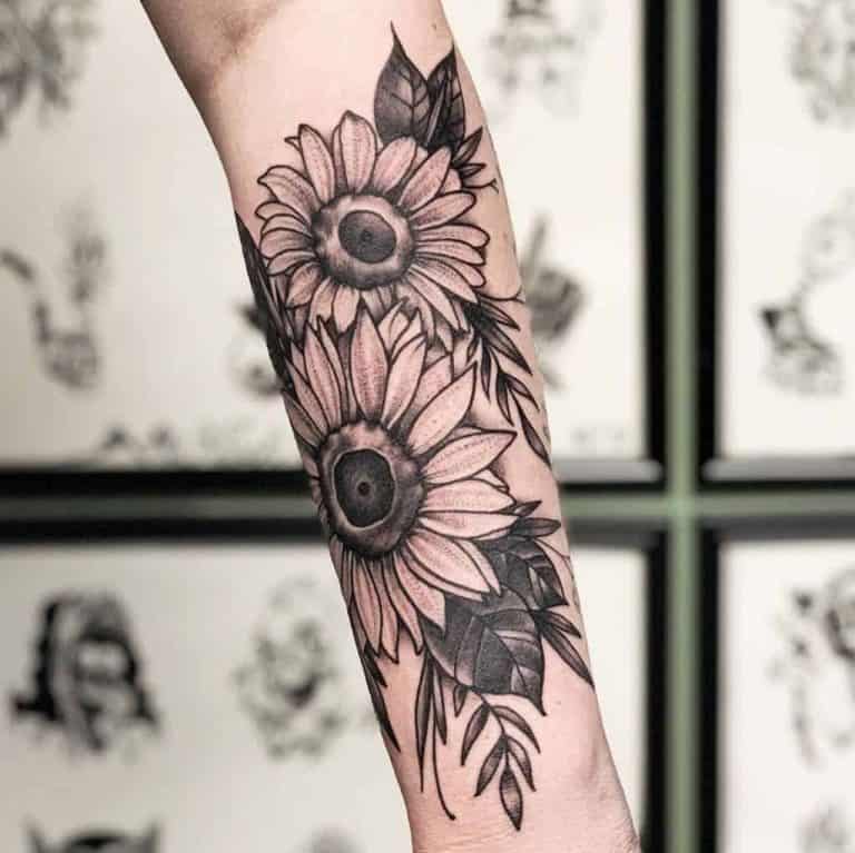 large black and grey realistic tattoo on woman's forearm of a bouquet of sunflowers