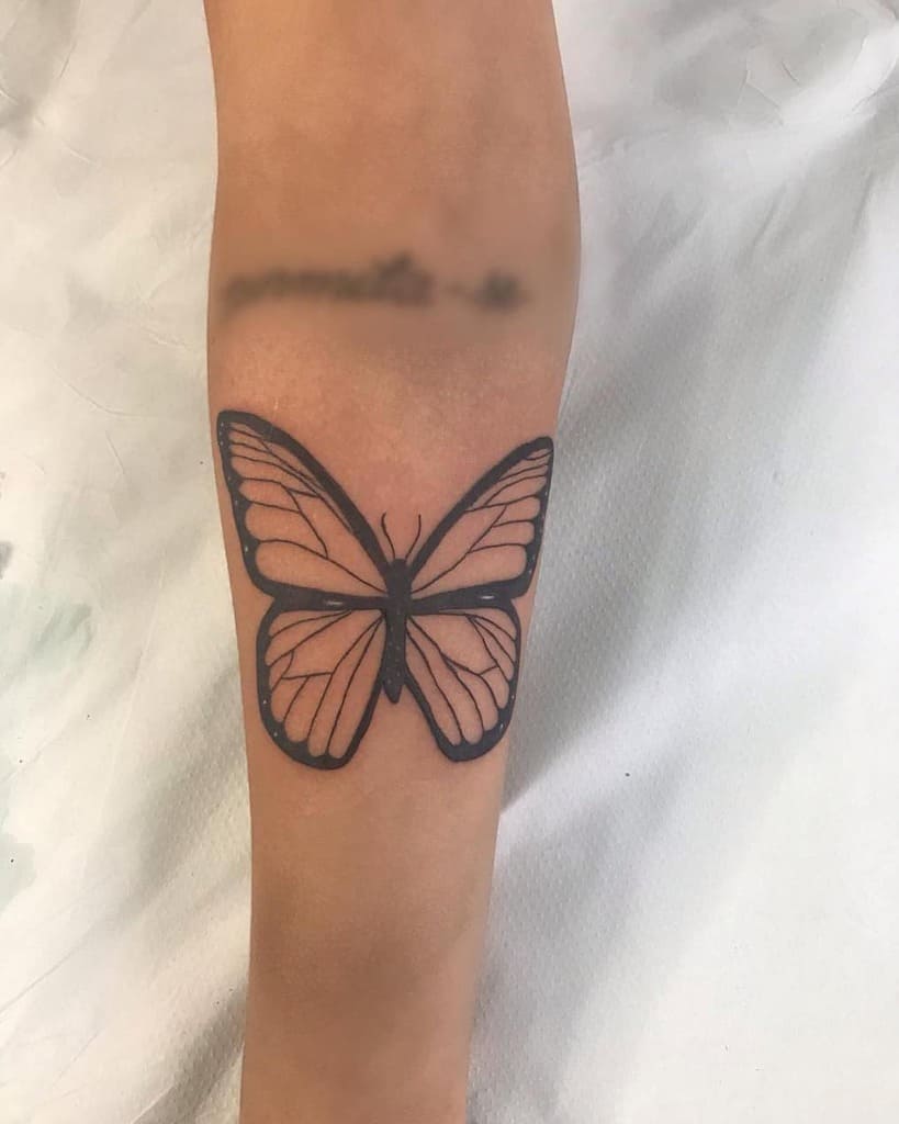 Minimalist butterfly tattoo on the forearm with bold black outlines and delicate shading for a sleek and elegant design.