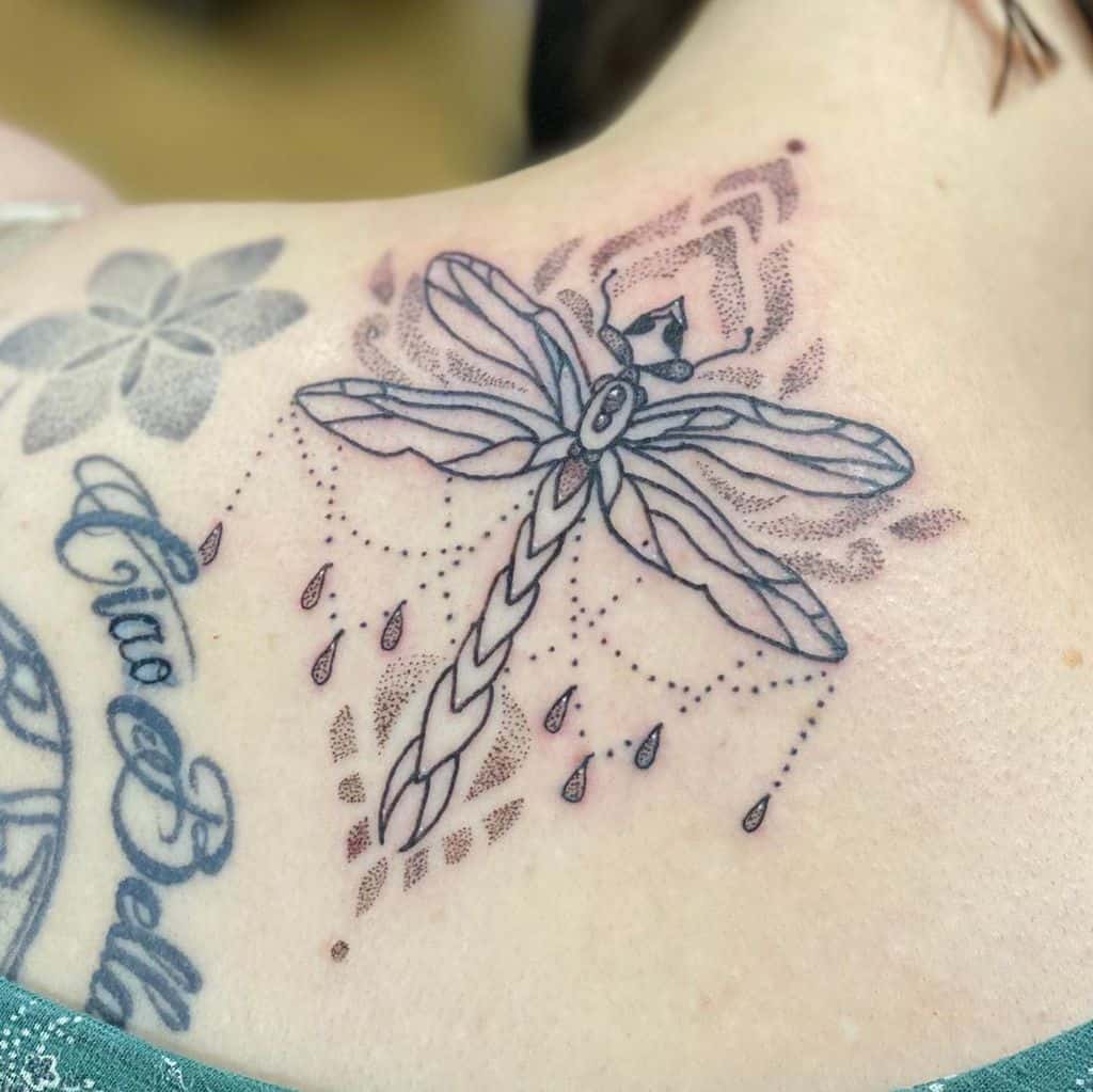 Elegant ornamental dragonfly tattoo on the shoulder, featuring bead details, fine linework, and soft dot shading for a delicate look.