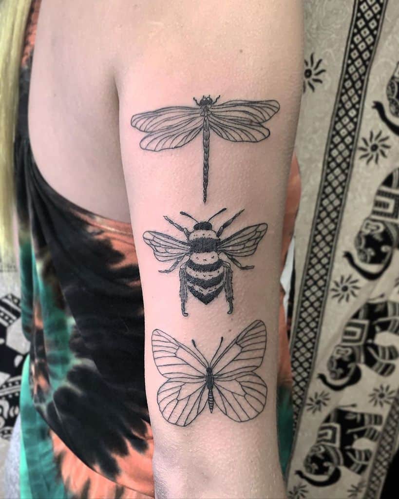 Minimalist black ink tattoo on the upper arm featuring a dragonfly, bee, and butterfly in a vertical arrangement with fine linework.