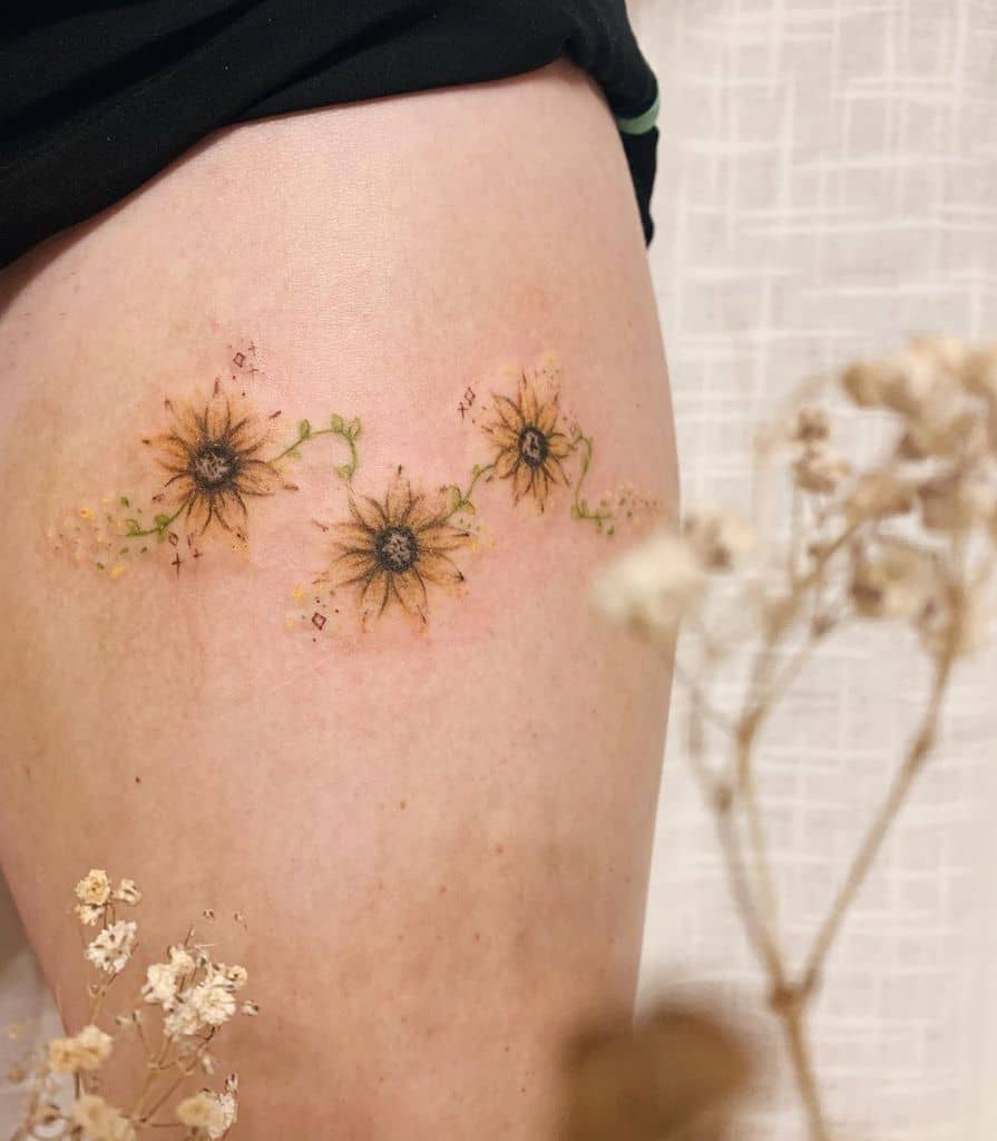 Delicate sunflower tattoo on a thigh with small green vines