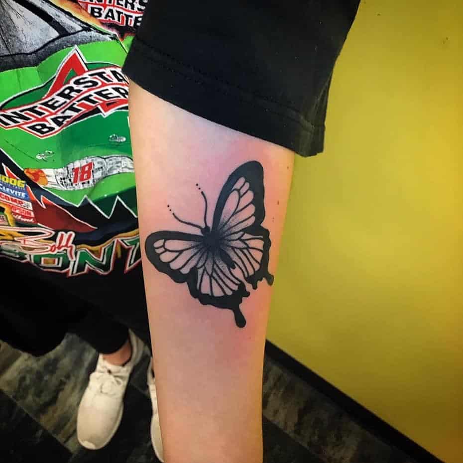 Bold black and grey butterfly tattoo on the forearm with intricate shading and a striking contrast for a dynamic look.