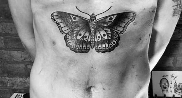 Large black and gray butterfly tattoo on the lower abdomen, featuring intricate dotwork shading and detailed wing patterns.