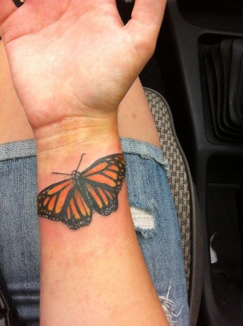 Realistic monarch butterfly tattoo on the wrist with vibrant orange and black details, creating a lifelike and elegant design.