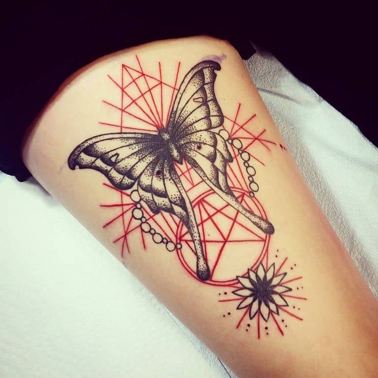 Black and gray butterfly tattoo on the thigh, featuring intricate dotwork, geometric red line patterns, and celestial accents for a bold design.