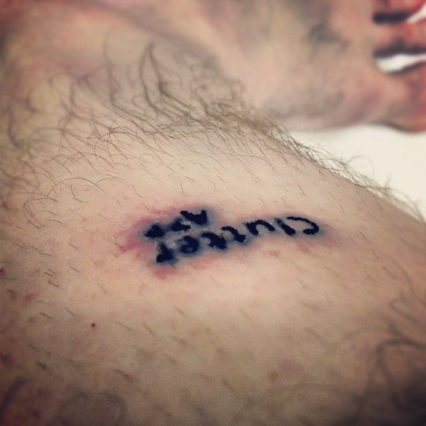 Close-up of a healing tattoo with 'cut here' in black ink, showing signs of scabbing around the letters