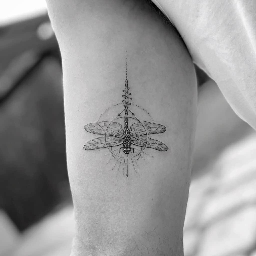 Intricate geometric dragonfly tattoo on the upper arm, featuring fine linework, symmetrical details, and celestial-inspired elements.