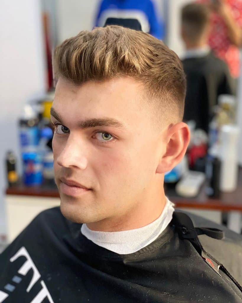 A High Fade Cut Paired With Slicked Back Hair On Top