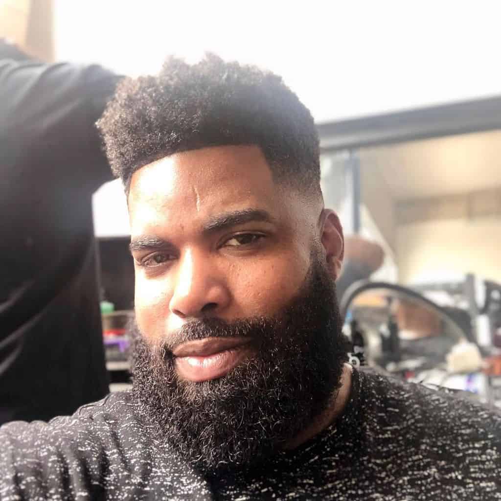 A High Top Haircut With Highly Textured Hair On Top And An Undercut