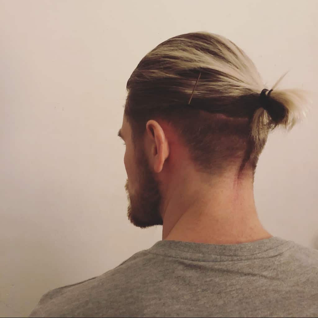 A Man Bun Hairdo With Undercut And Spikes Sticking Out From The Knot