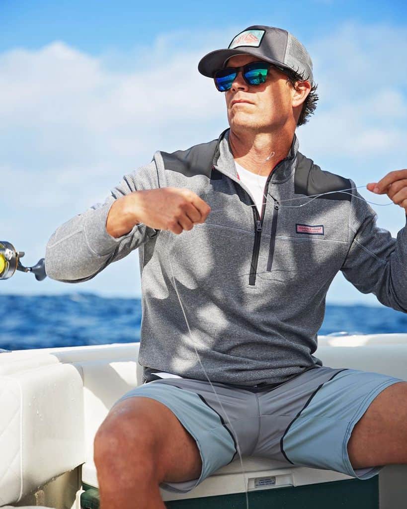 A Man On A Boat Preparing A Fishing Line And Wearing Mirrored Sunglasses