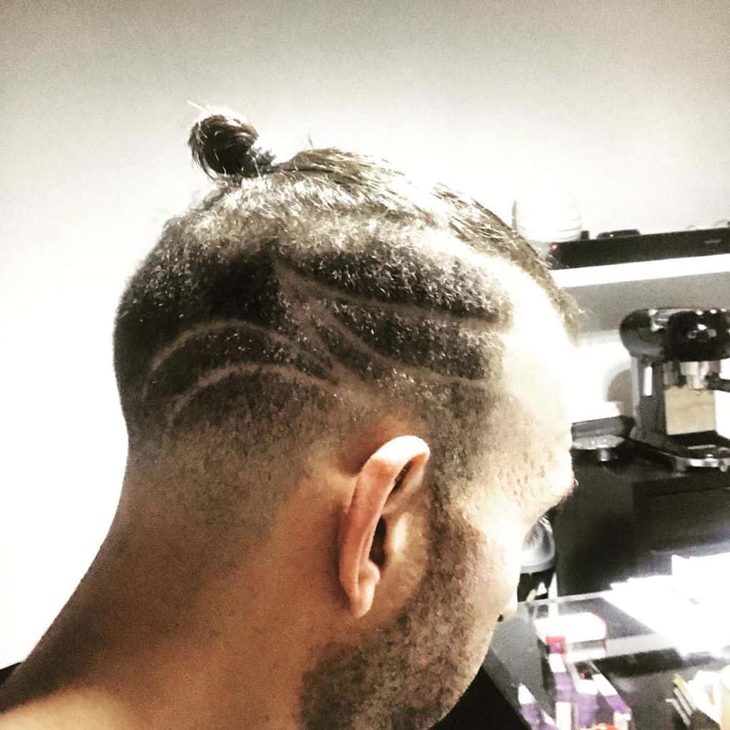 A Man Wearing A Man Bun Undercut With Beautiful Designs On The Undercut
