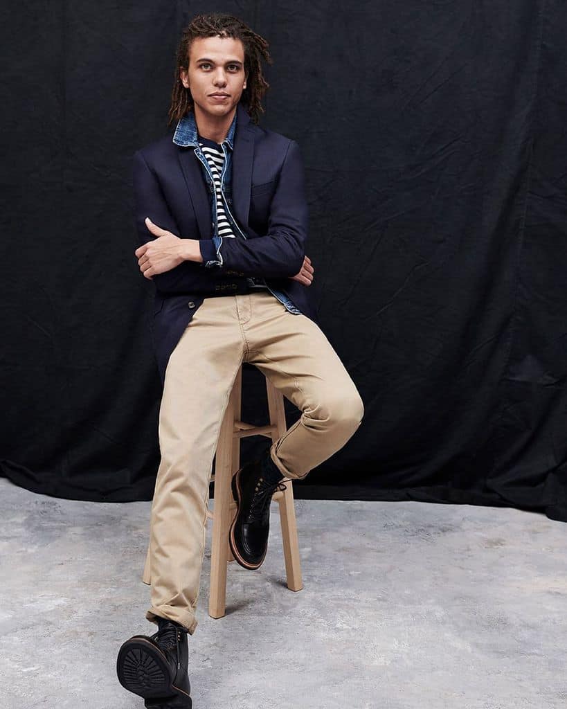 A Man Wearing A Modern Preppy Outfit With A Navy Blazer Over A Denim Jacket And Striped Shirt