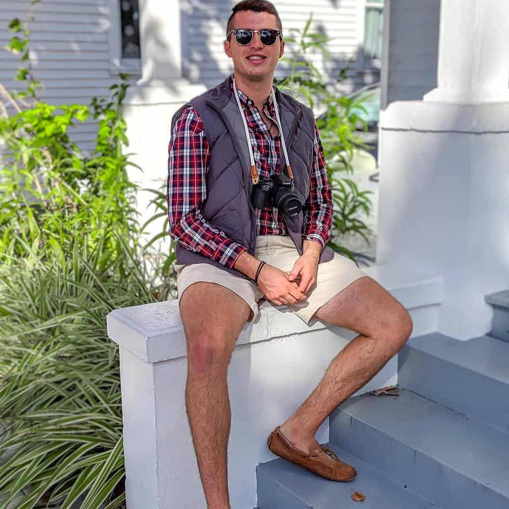 A Man Wearing Loafers With No Socks, Smiling And Sitting On A Wall