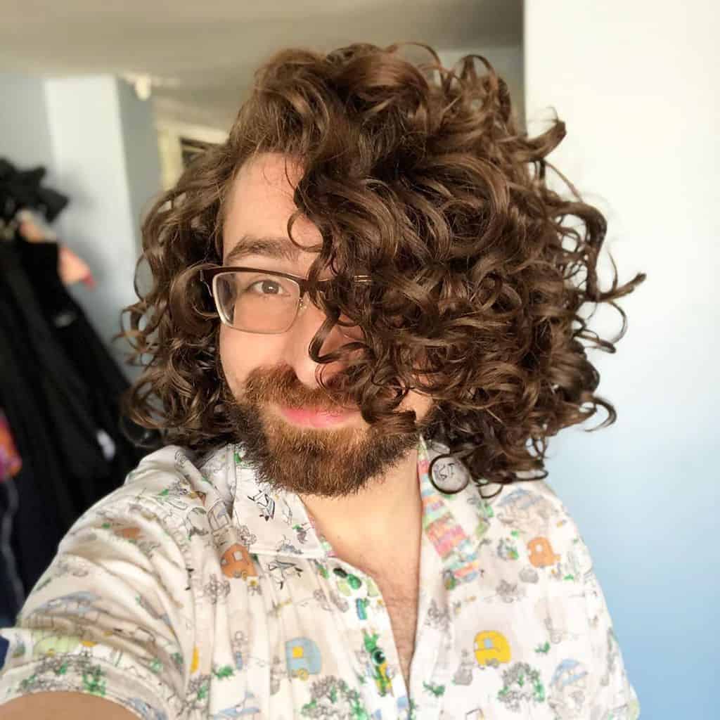 A Man Wearing Long Curly Locks Reaching The Shoulder Length