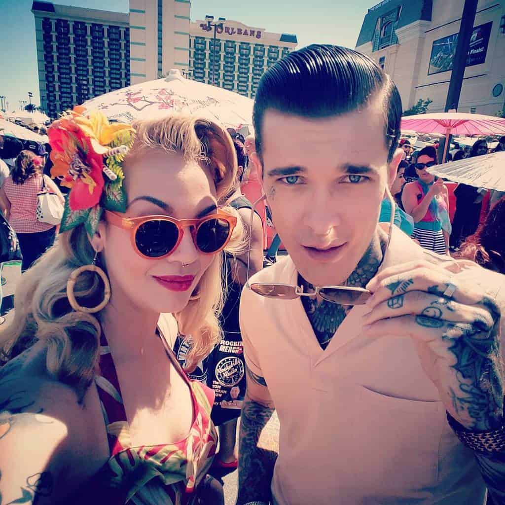 A Woman And Man Dressed In Full Rockabilly Outfits At An Outdoor Event