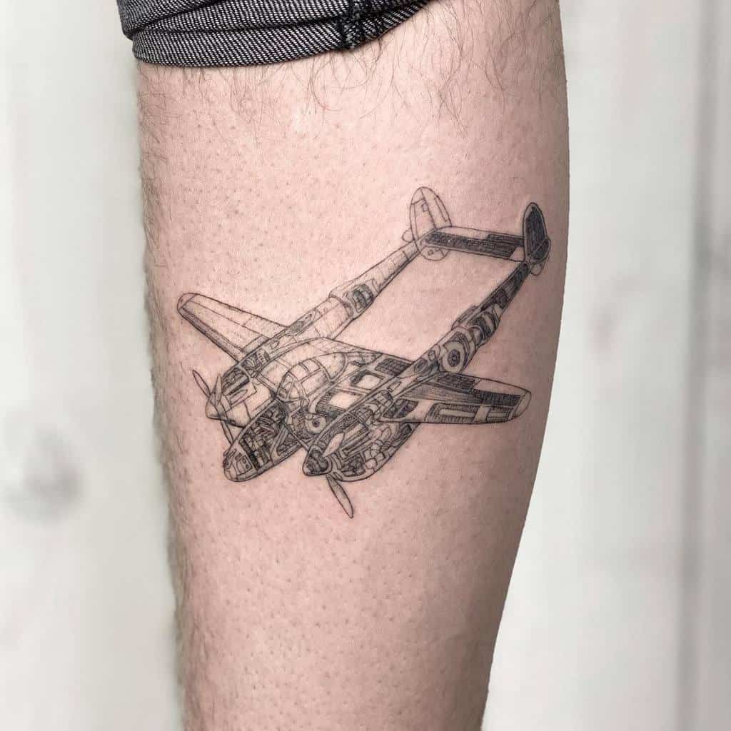 Tattoo of a detailed airplane on a person's upper leg, created with single needle precision, visible against a light background