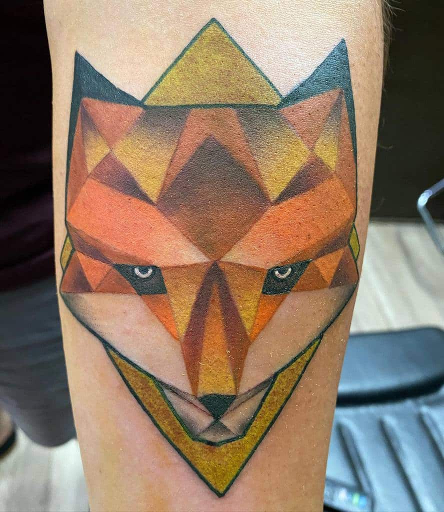 Geometric fox tattoo with shades of orange, brown, and yellow on a person's arm intricately blends modern design with natural beauty