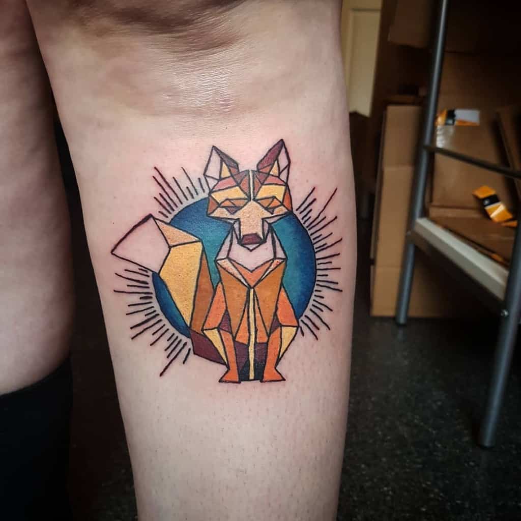 A striking geometric fox tattoo on the leg against a circular blue background with radiating lines