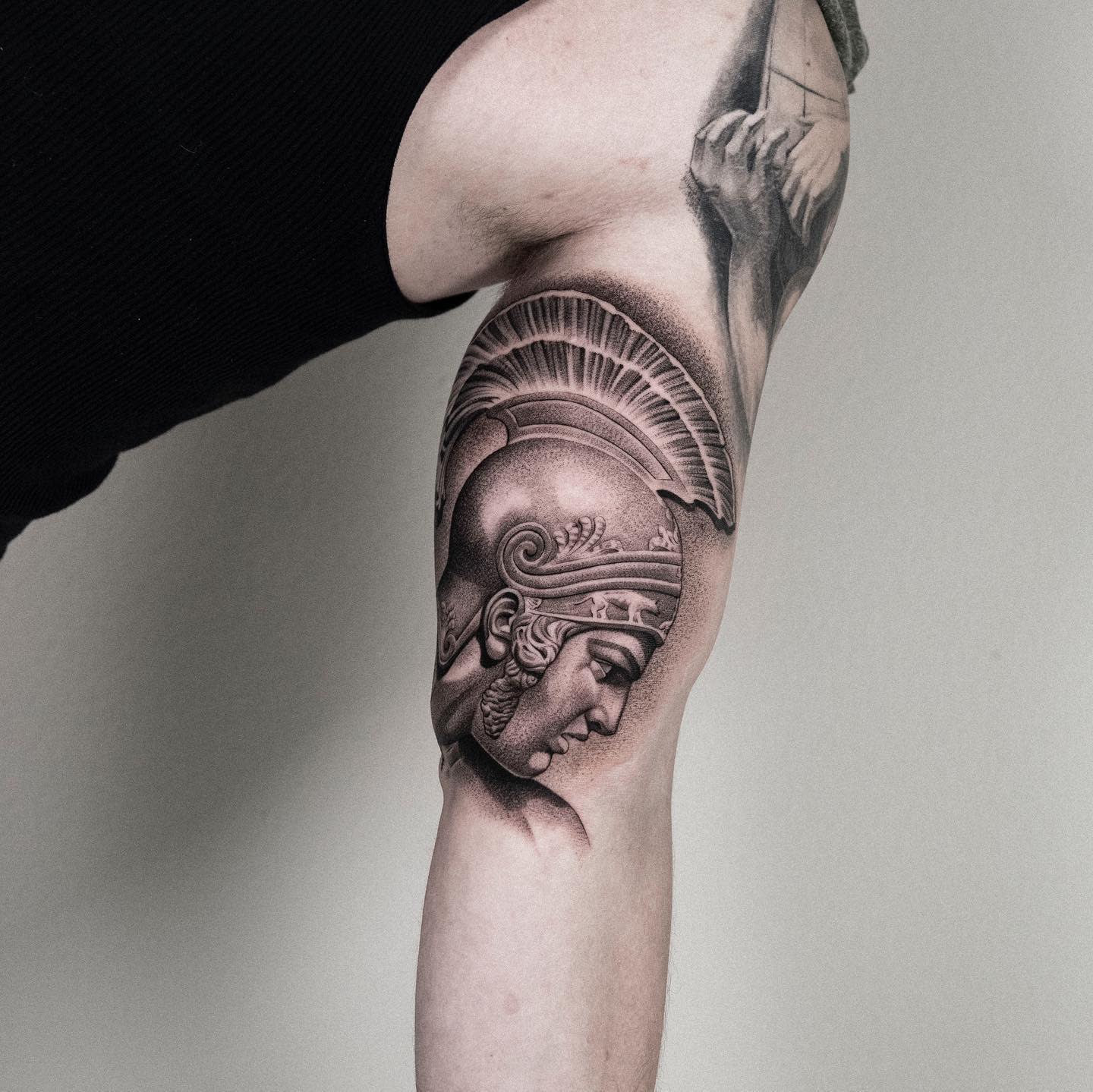 A detailed tattoo of a helmeted warrior Achilles on an upper arm