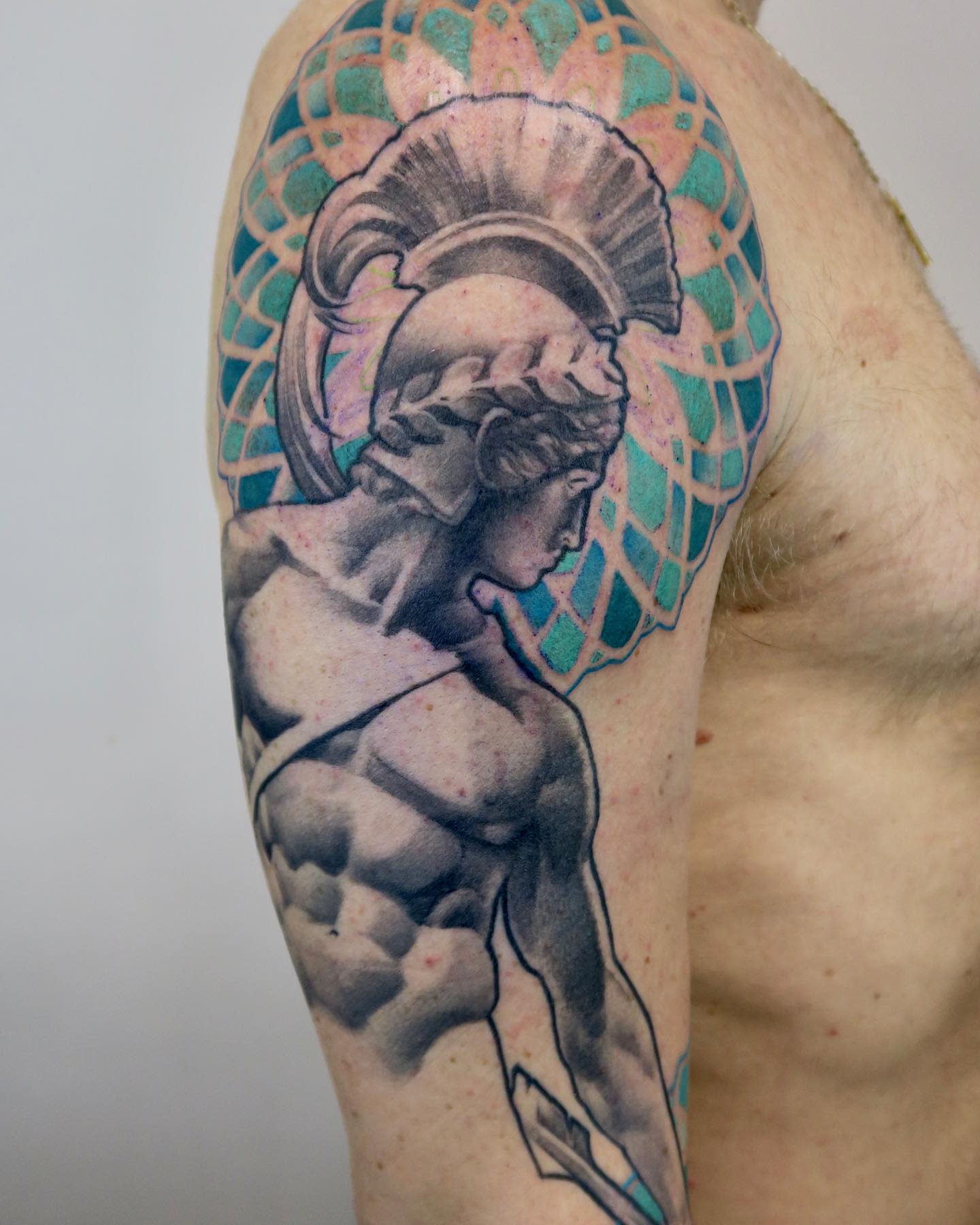 Tattoo of Achilles with a helmet on an upper arm, featuring intricate detail