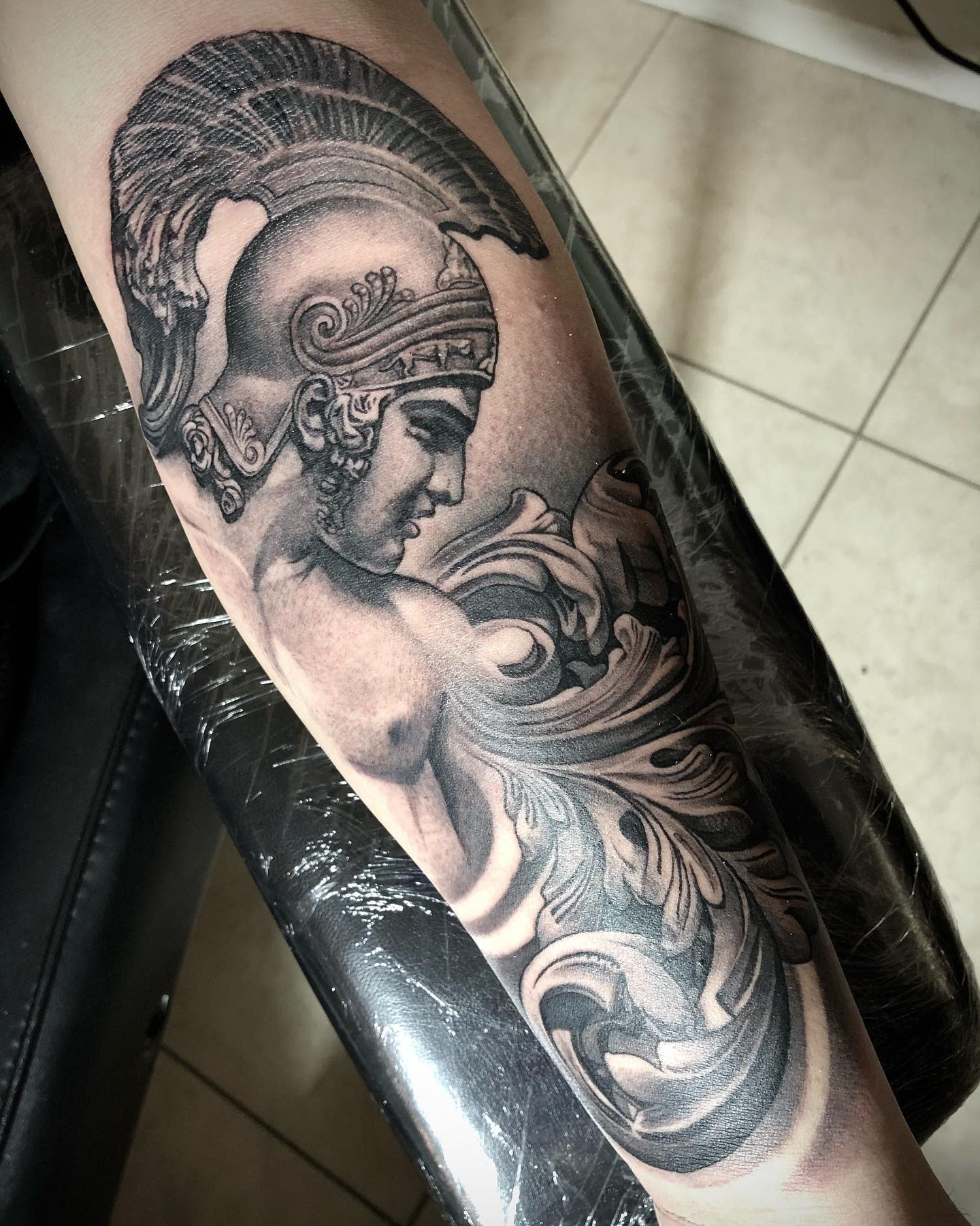 Tattoo of Achilles with a helmet and intricate details on a forearm