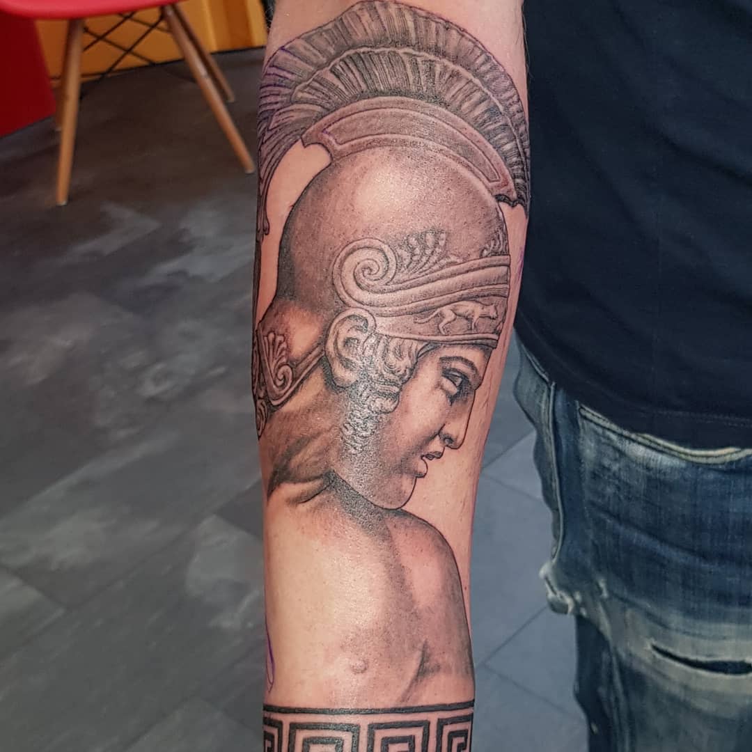 Black and white tattoo of a helmeted warrior Achilles on a forearm