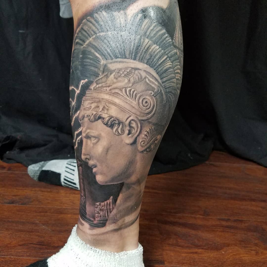 Tattoo of Achilles bust on a leg, with intricate helmet details