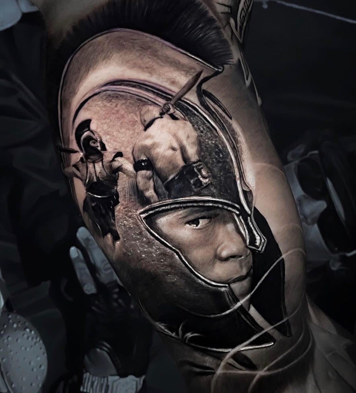 Tattoo of Brad Pitt playing Achilles in a helmet with a detailed face and another figure wielding a sword