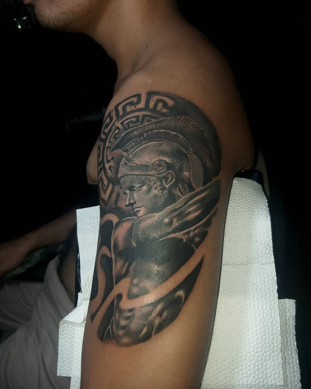 A detailed tattoo of Achilles on an upper arm