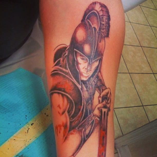 Tattoo of Brad Pitt playing Achilles holding a sword on a forearm