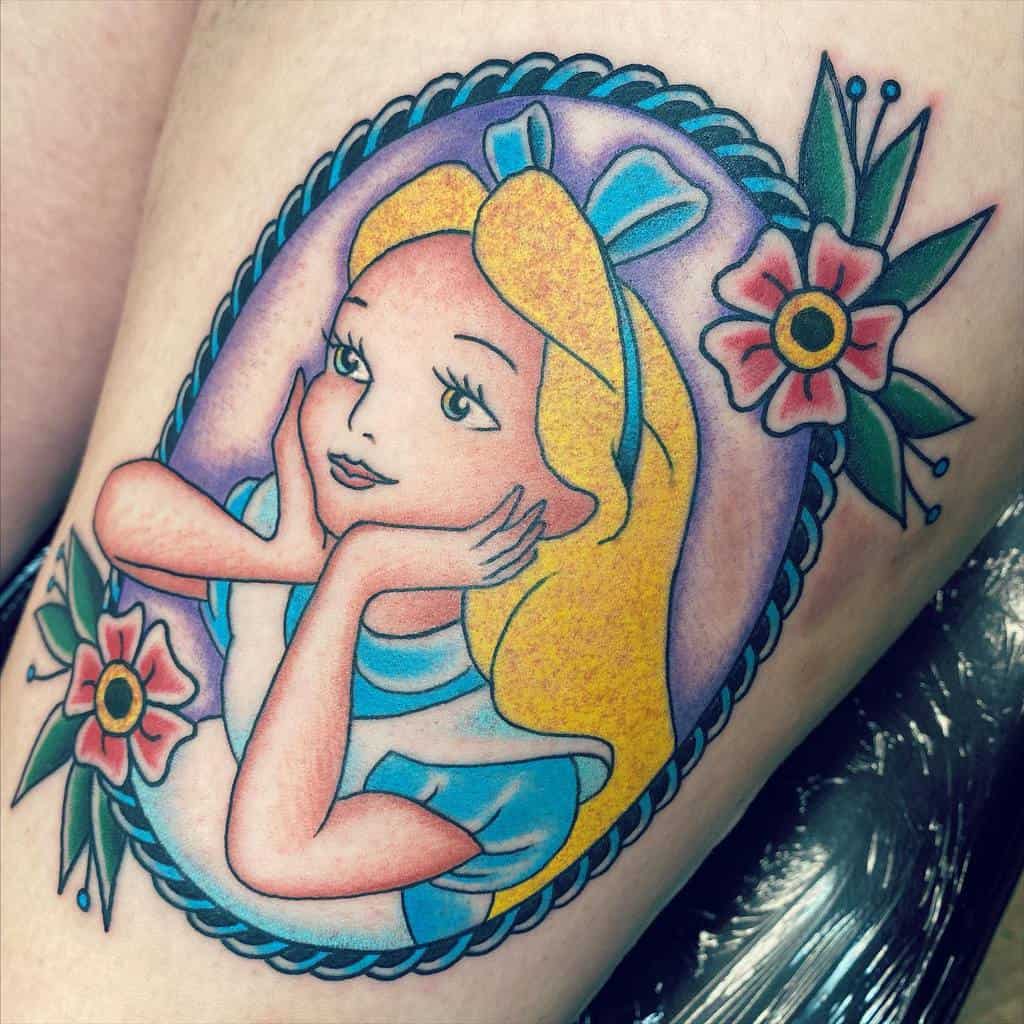 Colorful tattoo of Alice from Alice in Wonderland, framed by flowers, wearing her iconic blue dress and bow