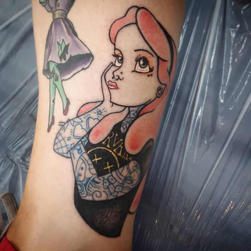 Colorful tattoo of Alice from Alice in Wonderland, with pink hair, wearing a t-shirt, and blue inked tattoos on her both arms