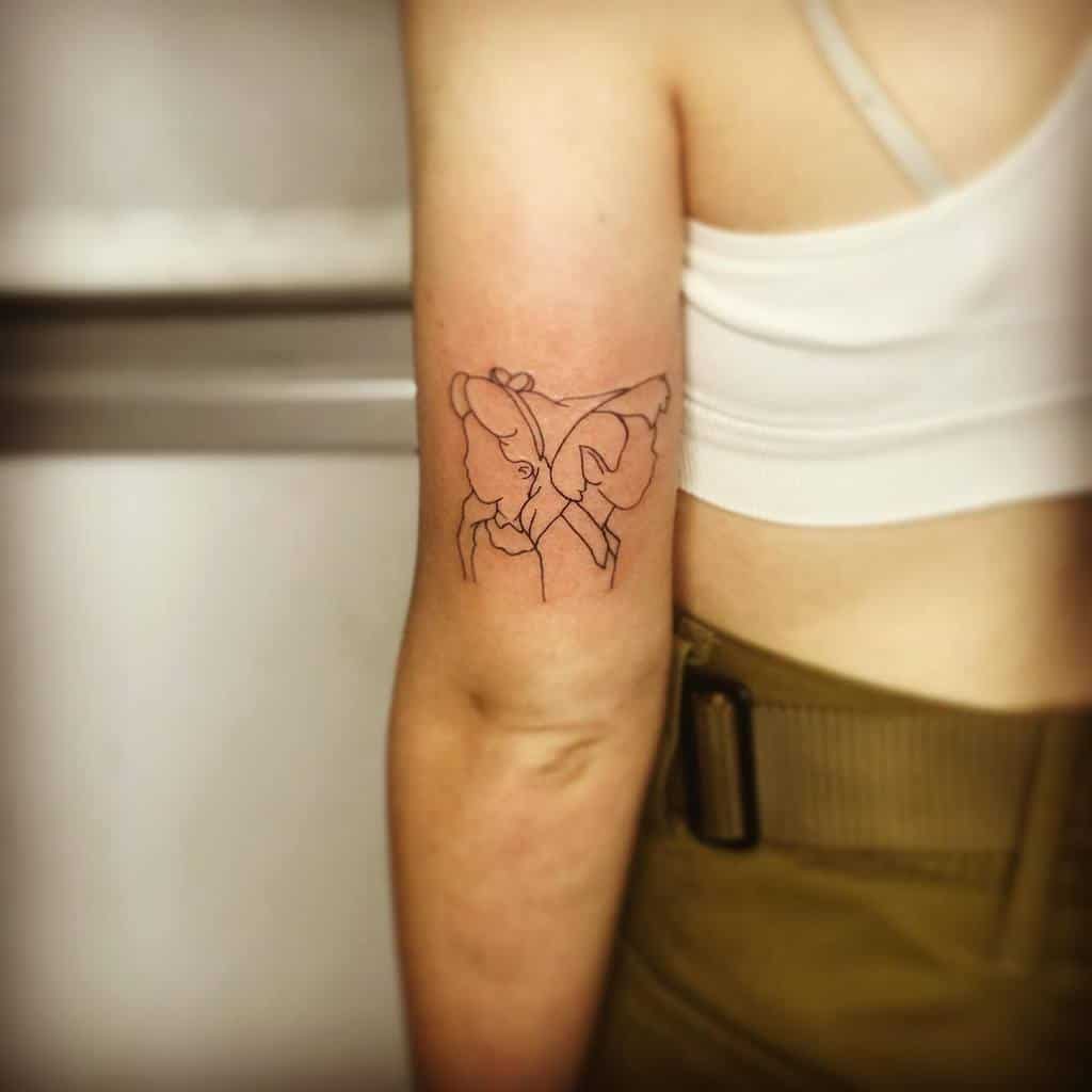 Minimalistic tattoo of Alice and Peter Pan, with their profiles forming the shape of a butterfly, creating a subtle and artistic design