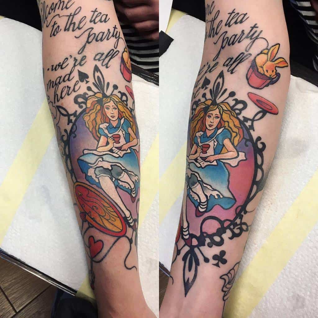 Colorful tattoo of Alice from Alice in Wonderland, sitting at a tea party with a cup in her hand, framed by whimsical decorations, and the words 'Welcome to the tea party, we're all mad here' written above her, with rabbit in gift and heart