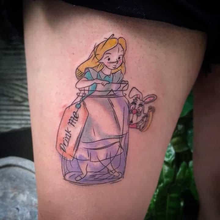 Colorful tattoo of Alice from Alice in Wonderland, inside a bottle labeled 'Drink Me,' with the White Rabbit peeking out from behind her