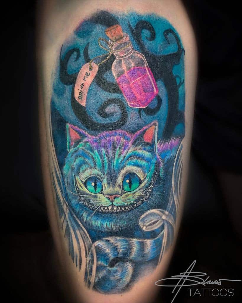A vibrant Cheshire Cat tattoo with glowing eyes and a "Drink Me" bottle, set against swirling blue