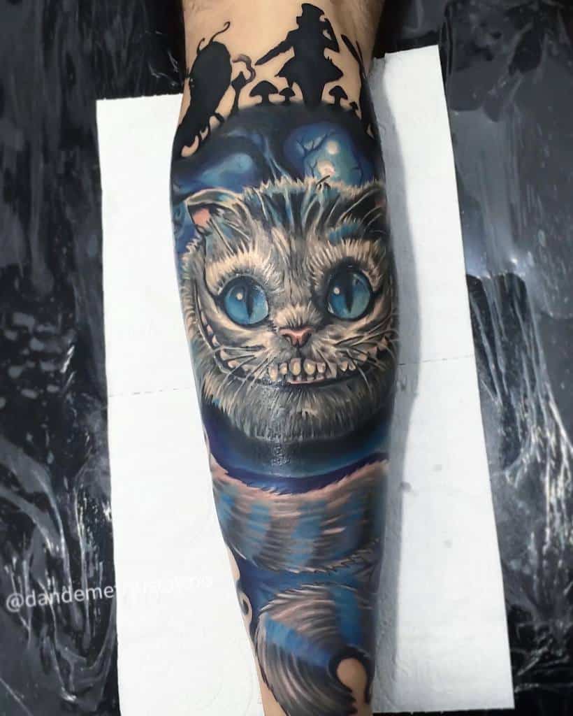 A striking Cheshire Cat tattoo with piercing blue eyes, framed by Alice and Wonderland silhouettes above