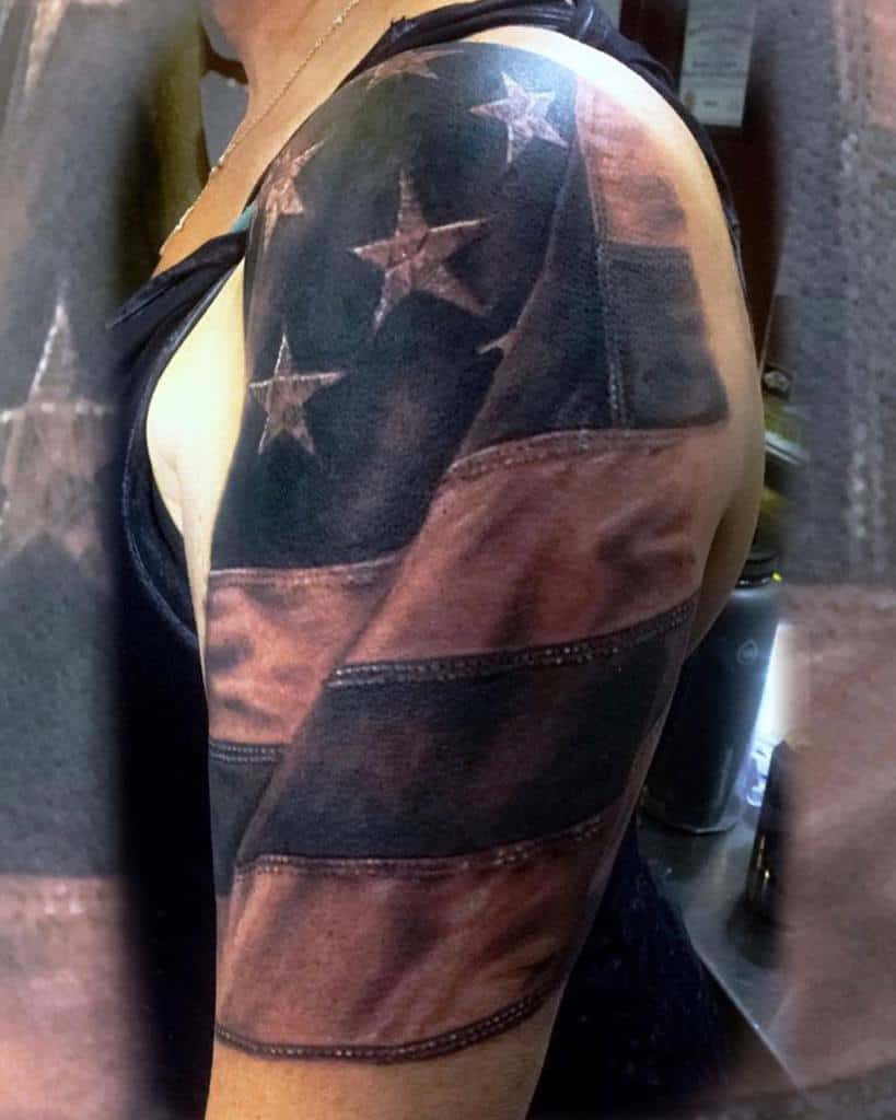 Arm tattoo of a realistic, weathered American flag with stars and stripes