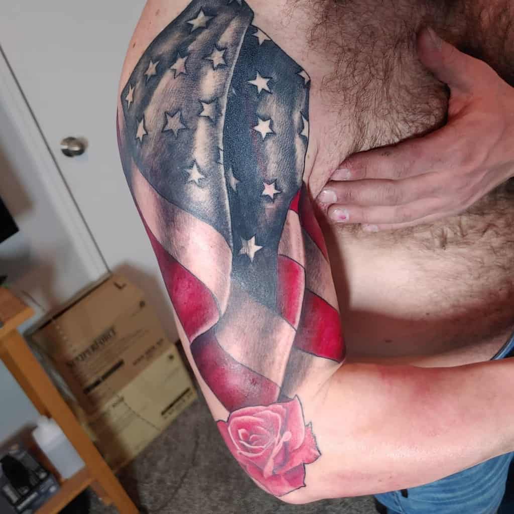 Tattoo of a waving American flag and a rose on a man's upper arm
