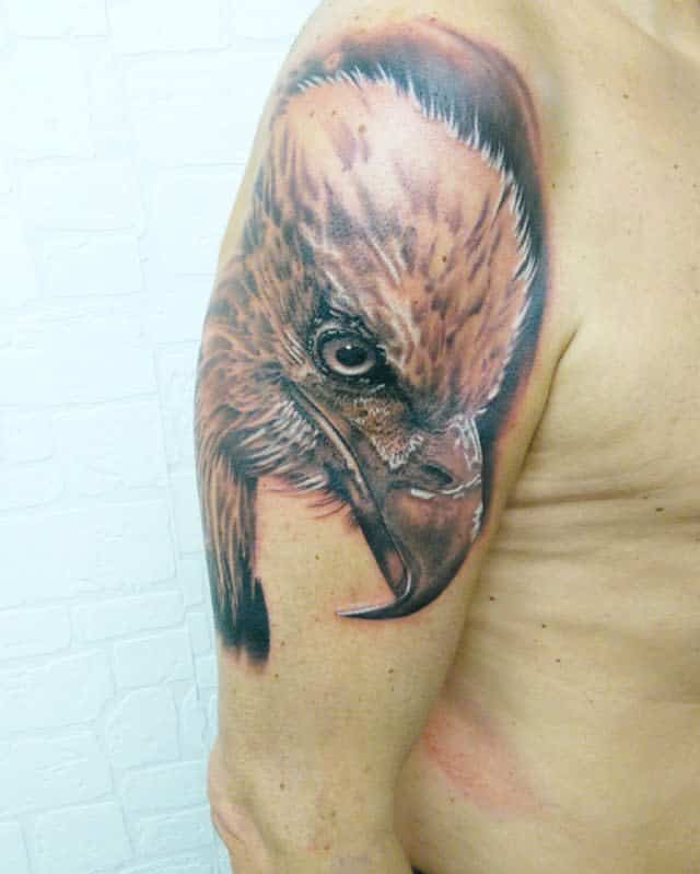 A detailed tattoo of an eagle's head on an upper arm