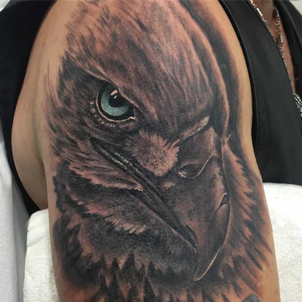 Close-up of a detailed eagle head tattoo on an upper arm, showcasing the bird's eye and beak
