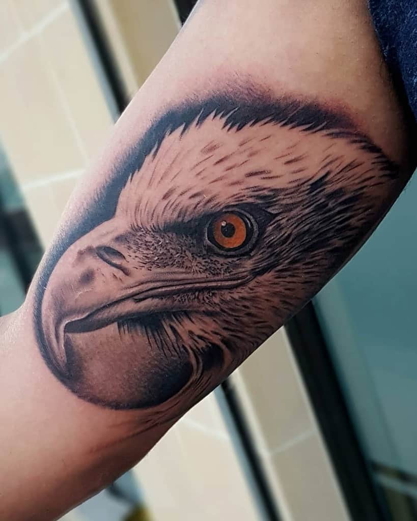Close-up of a detailed eagle head tattoo on an arm with the eagle's eye striking and vividly colored