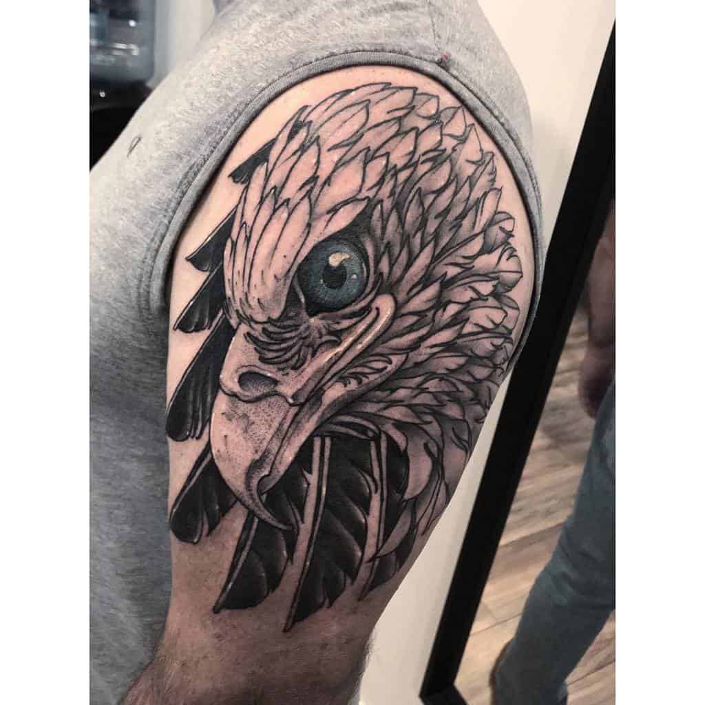 A detailed black and white eagle head tattoo on a bicep