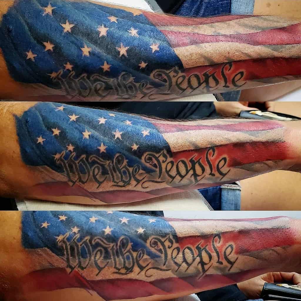 Tattoo of the American flag and "We the People" text on a person's arm